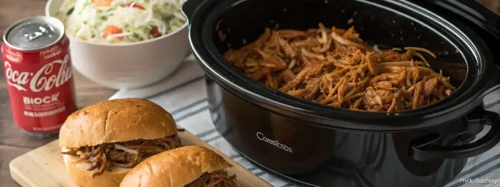 a crock pot with pulled pork and sandwiches