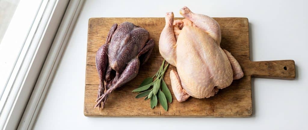Whole raw guinea fowl on a wooden board