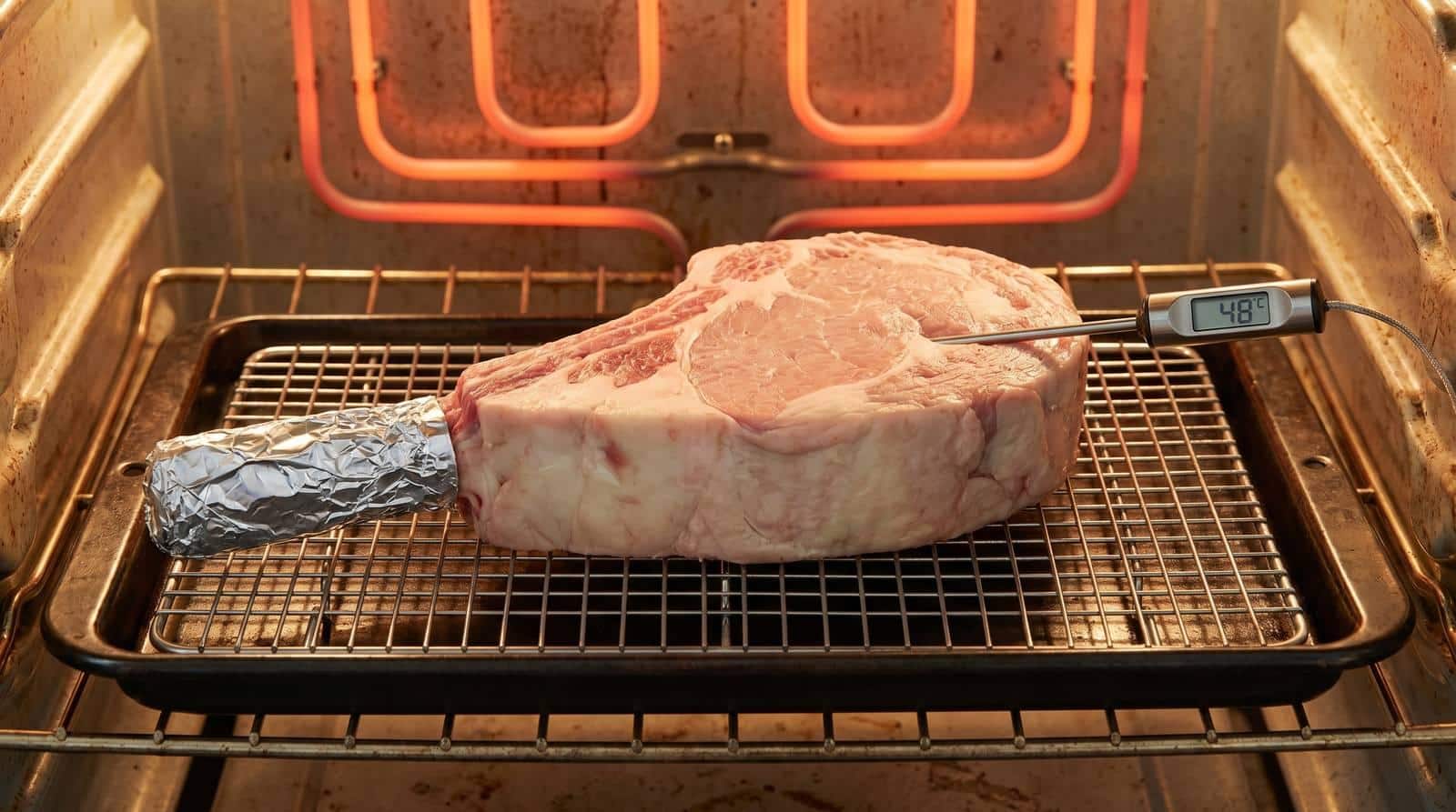 How to Reverse Sear a Tomahawk Steak: A 2026 Step-by-Step Guide 4 Tomahawk steak on a wire rack in a fan-forced oven with a digital probe thermometer inserted, reading approximately 48°C internal temperature